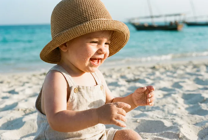 Gros plan d'un bébé jouant sur une plage de sable fin en Tunisie.