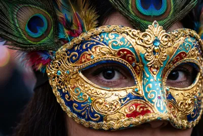 Gros plan sur un masque vénitien artisanal richement orné de dorures et de plumes.