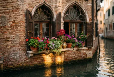 Gros plan sur une fenêtre gothique vénitienne avec fleurs et reflets d'eau sur briques