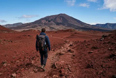 Randonneur marchant sur le sol rouge désertique de la Plaine des Sables