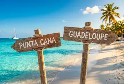 Panneaux directionnels indiquant Punta Cana et la Guadeloupe dans une eau turquoise.