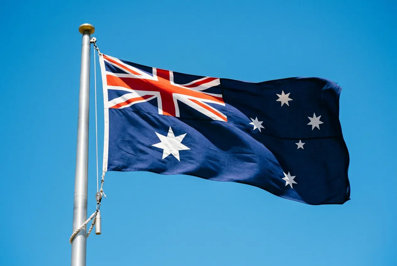 Le drapeau national australien flottant dans un ciel bleu dégagé.